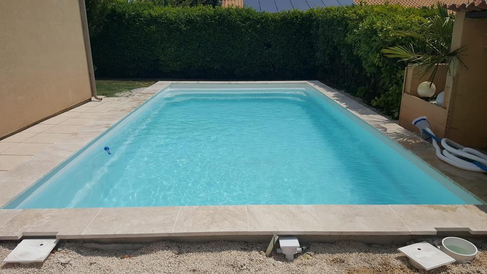 Bassin rectangulaire bordé d'une haie et de margelles claires
