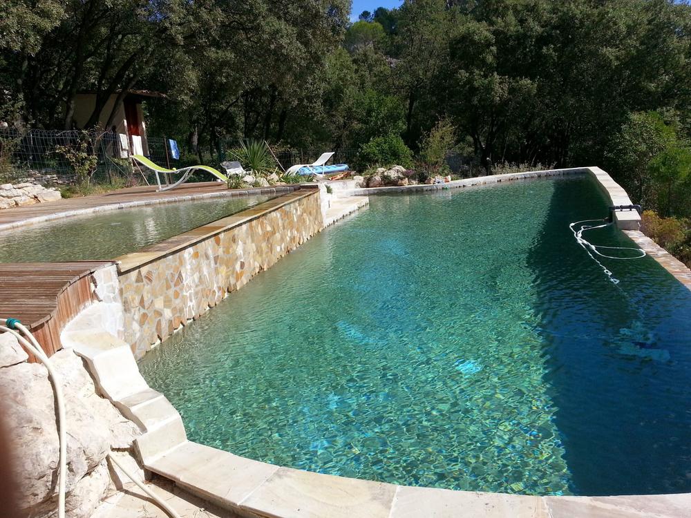 Piscine à débordement avec mur en pierre naturelle et terrasse en bois