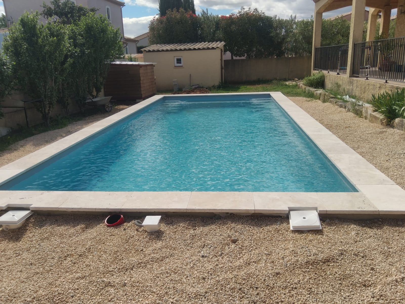 Piscine rectangulaire aux margelles de travertin construite par Naït Pool Services
