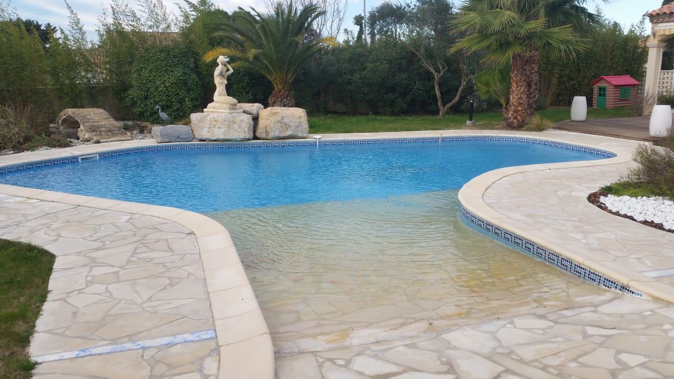 Piscine de forme libre avec dallage en pierre, réalisée par Naït Pool Services