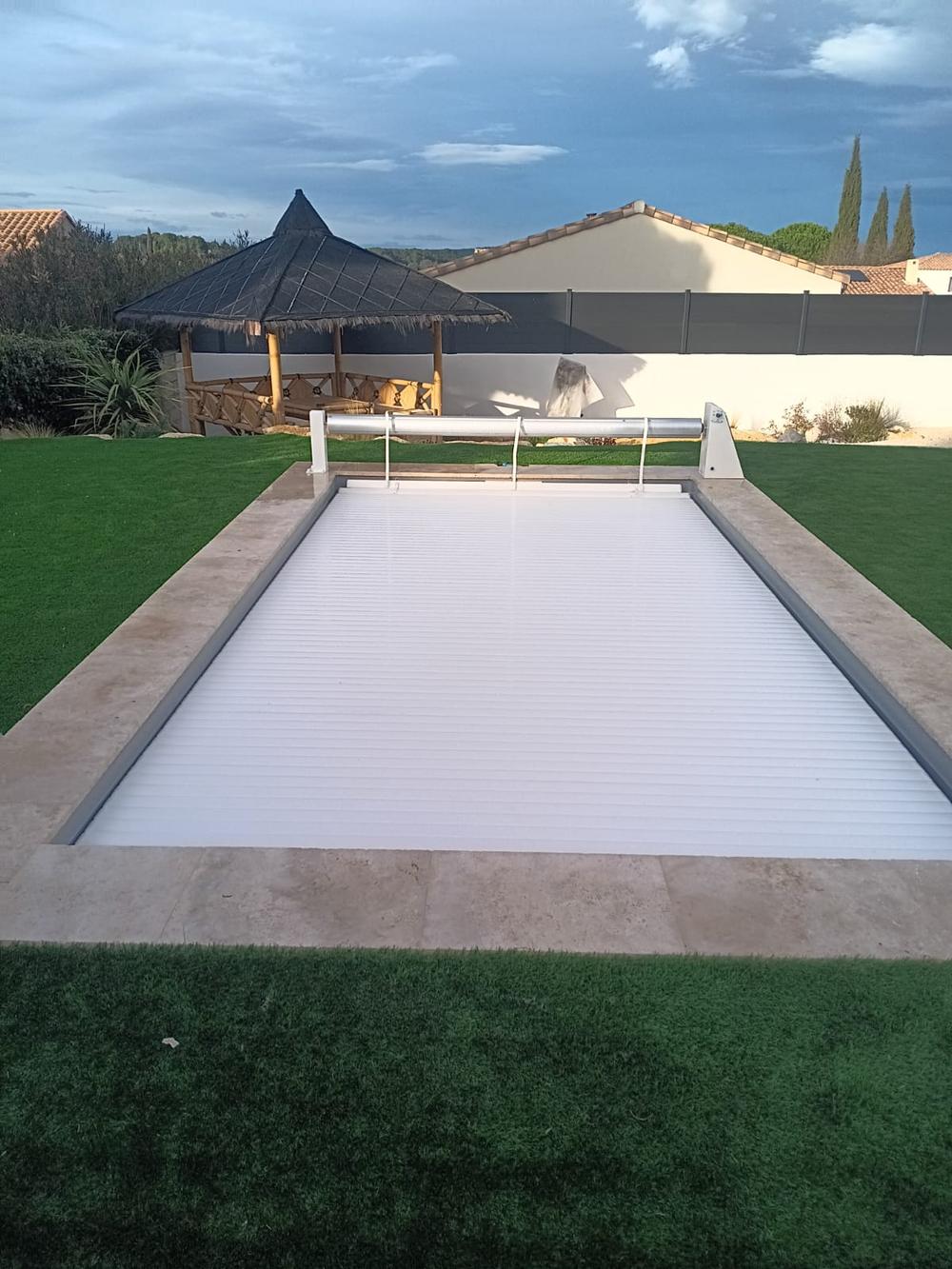 Piscine équipée d'un volet roulant immergé, bordée de pelouse